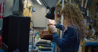 A luthier at MIRC inspects and sets up an acoustic guitar