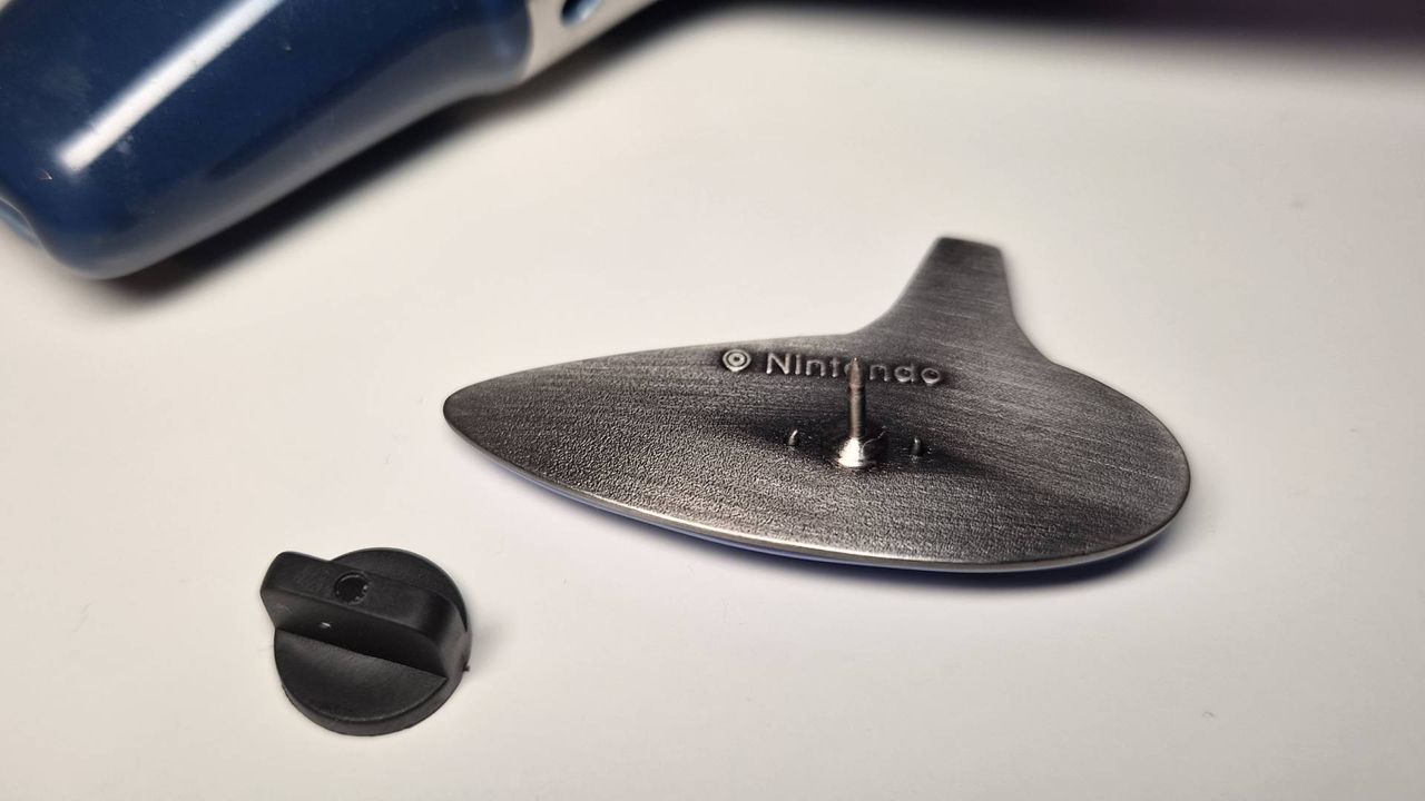 Photo of the back of the Ocarina of Time pin sitting on a white desk.