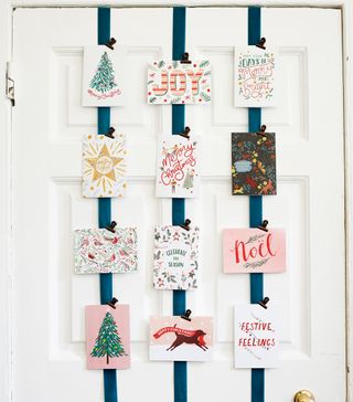 Christmas card display on blue ribbons against white door