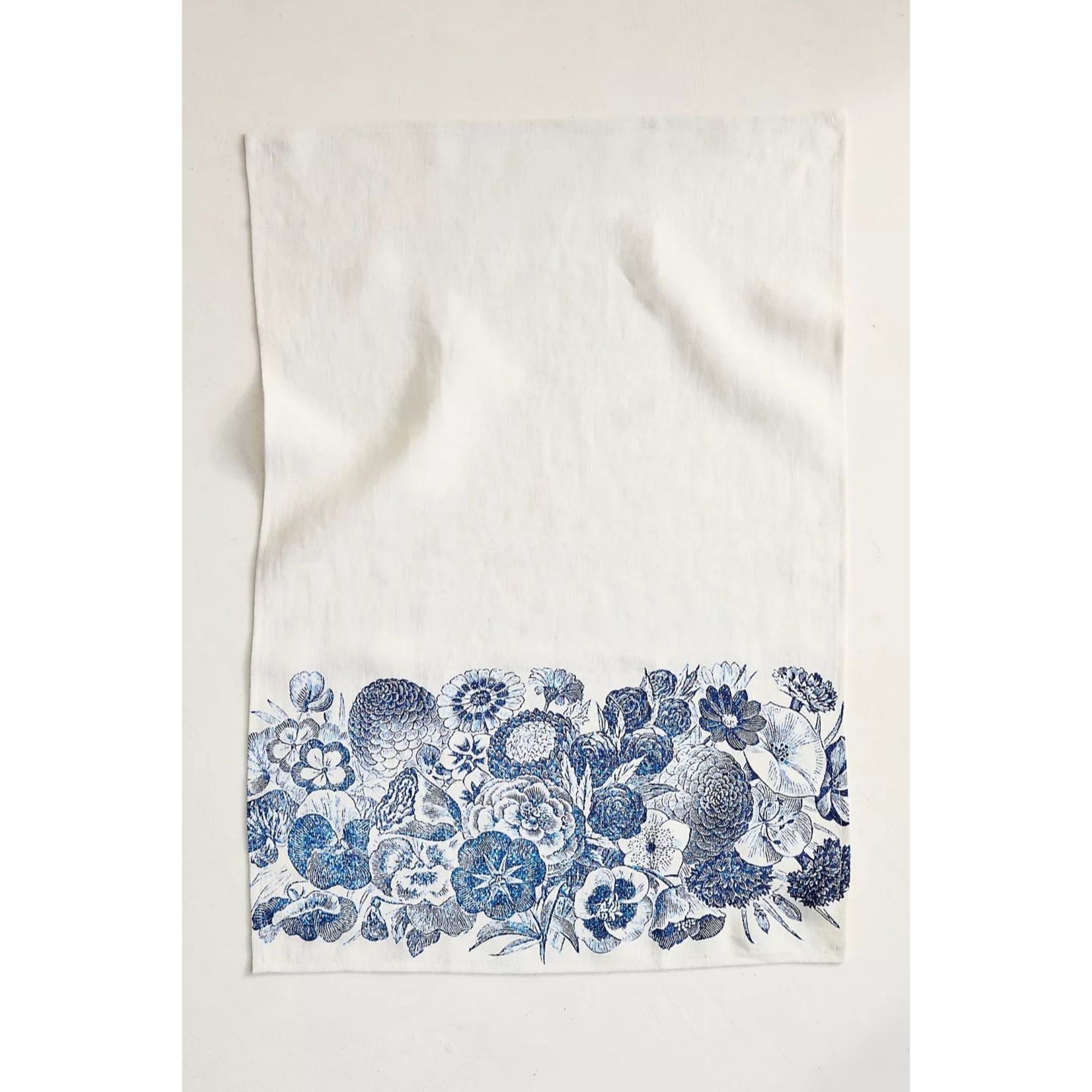 An off-white cotton tea towel with blue florall print running along the bottom edge as a band.