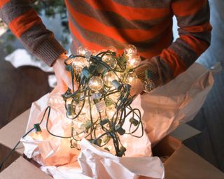 man holding unwrapped fairy lights