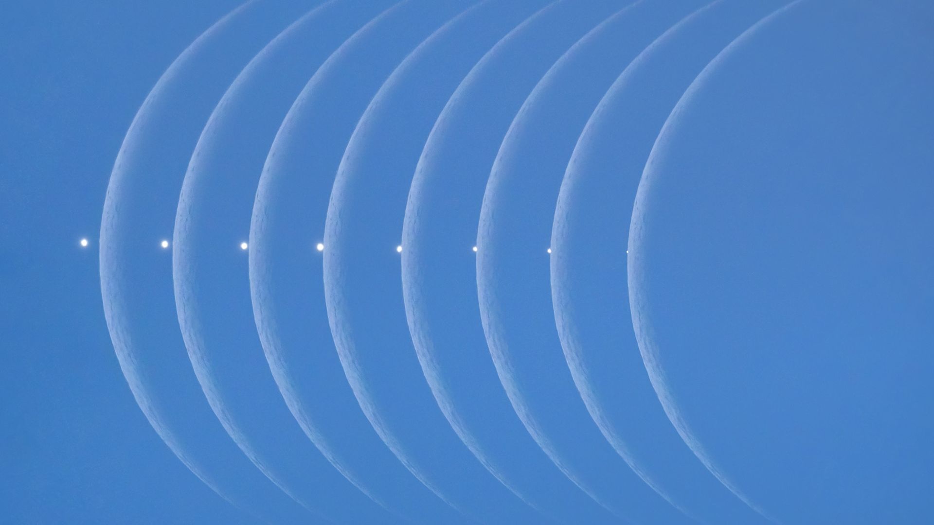 A series of moon phases against a blue sky.