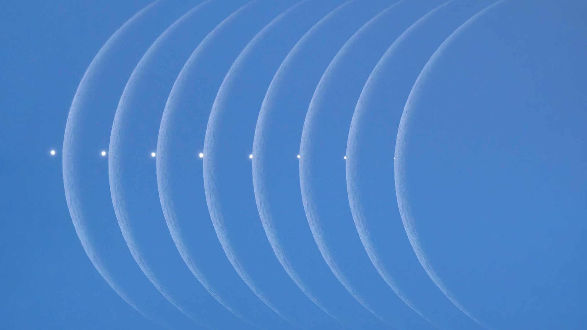 A series of moon phases against a blue sky.