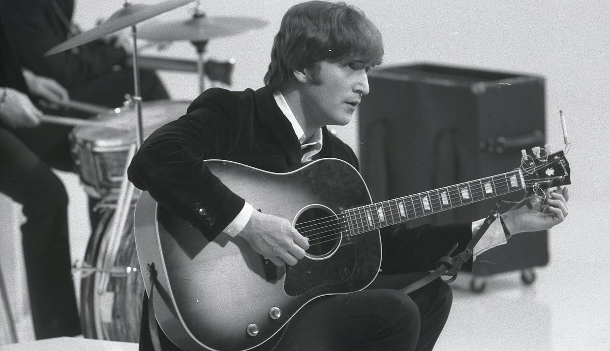 John Lennon holds an acoustic guitar while filming The Beatles&#039; &#039;Hard Day&#039;s Night&#039; movie at the Scala Theatre