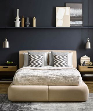 A bedroom with black wall panel decor with low-slung bed and shelving overhead
