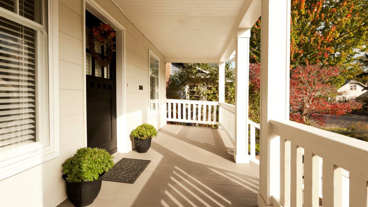 An american front porch with white woodwork and decking, a black front door - why hang pennies in a bag of water