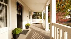 An american front porch with white woodwork and decking, a black front door - why hang pennies in a bag of water