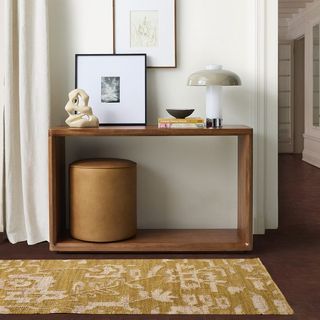 Yellow rug in hallway with console table, stool, lighting and artwork