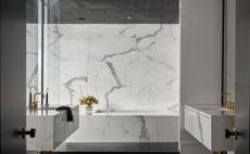 A bathroom with white marble walls and bathtub