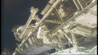 American astronaut Anne McClain moves between worksite locations on the S0 Truss of the International Space Station as she installs cabling for a backup power supply for robotic arm Canadarm2.