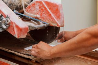 A person operating a wet saw to cut tiles