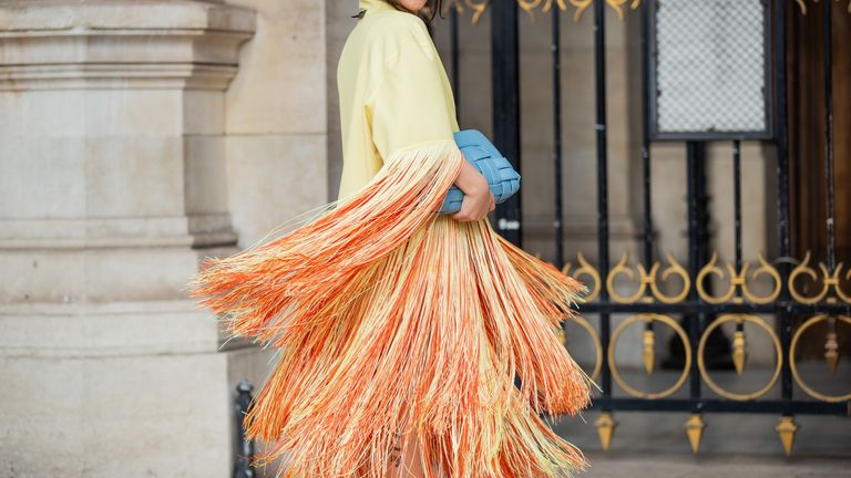 Gili Biegun seen wearing blue bag, yellow orange coat with fringes, orange platform heels outside Nanushka during Paris Fashion Week - Womenswear F/W 2022-2023 on March 01, 2022 in Paris, France
