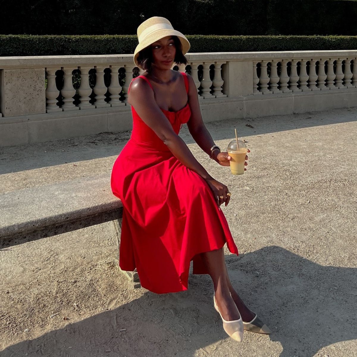 Woman wears red dress, white shoes, woven hat