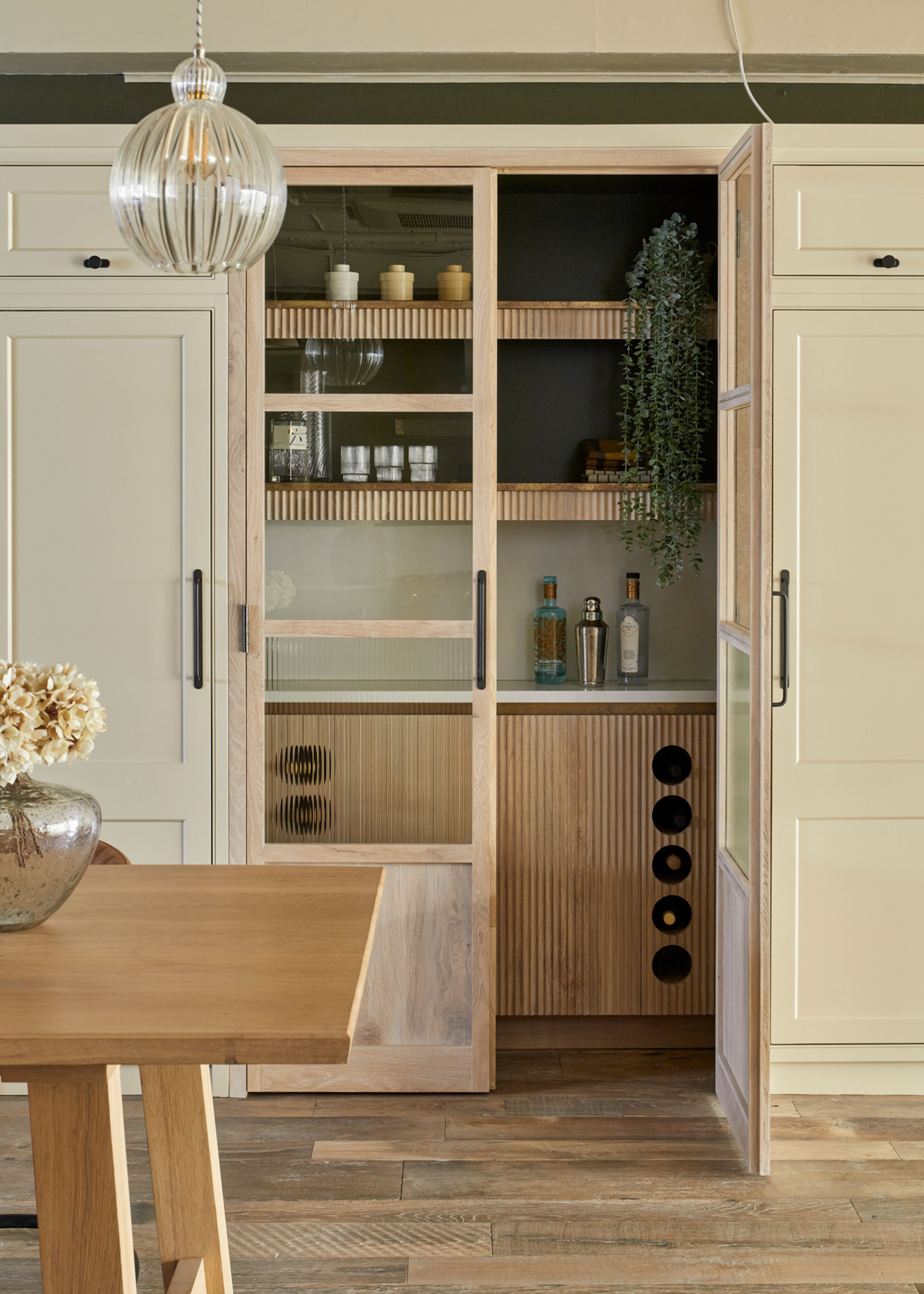 neutral soft green kitchen with walk in pantry with home bar