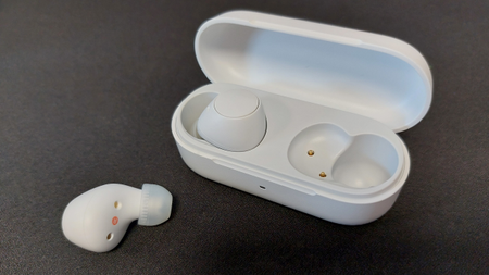 The Sony WF-C510 earbuds on a black desk mat. They are seen here inside their sleek charging case.