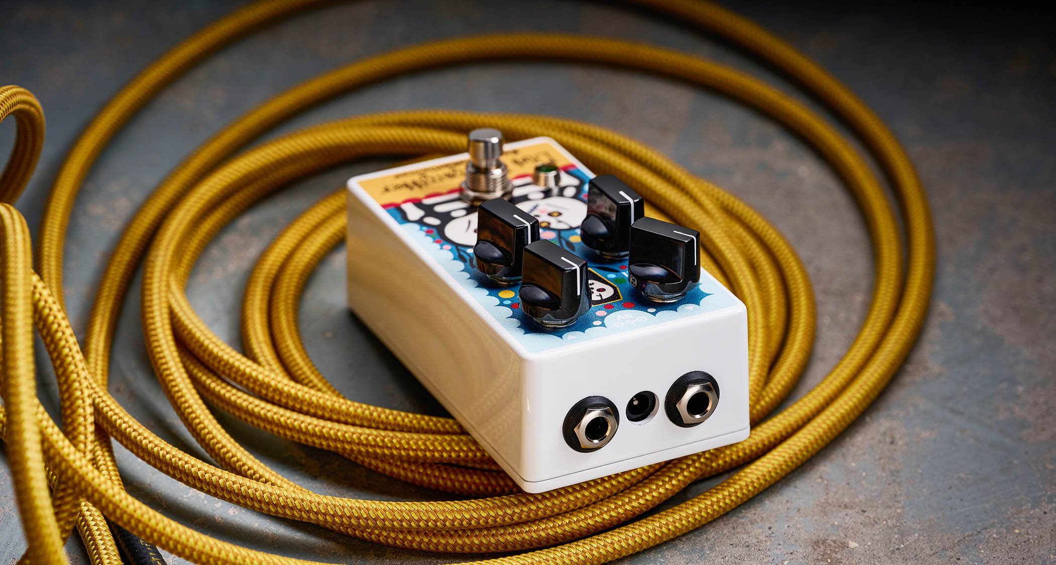 EarthQuaker Devices Rancho de la Luna Dirt Transmitter Fuzz Driver photographed on top of a tweed yellow guitar cable.