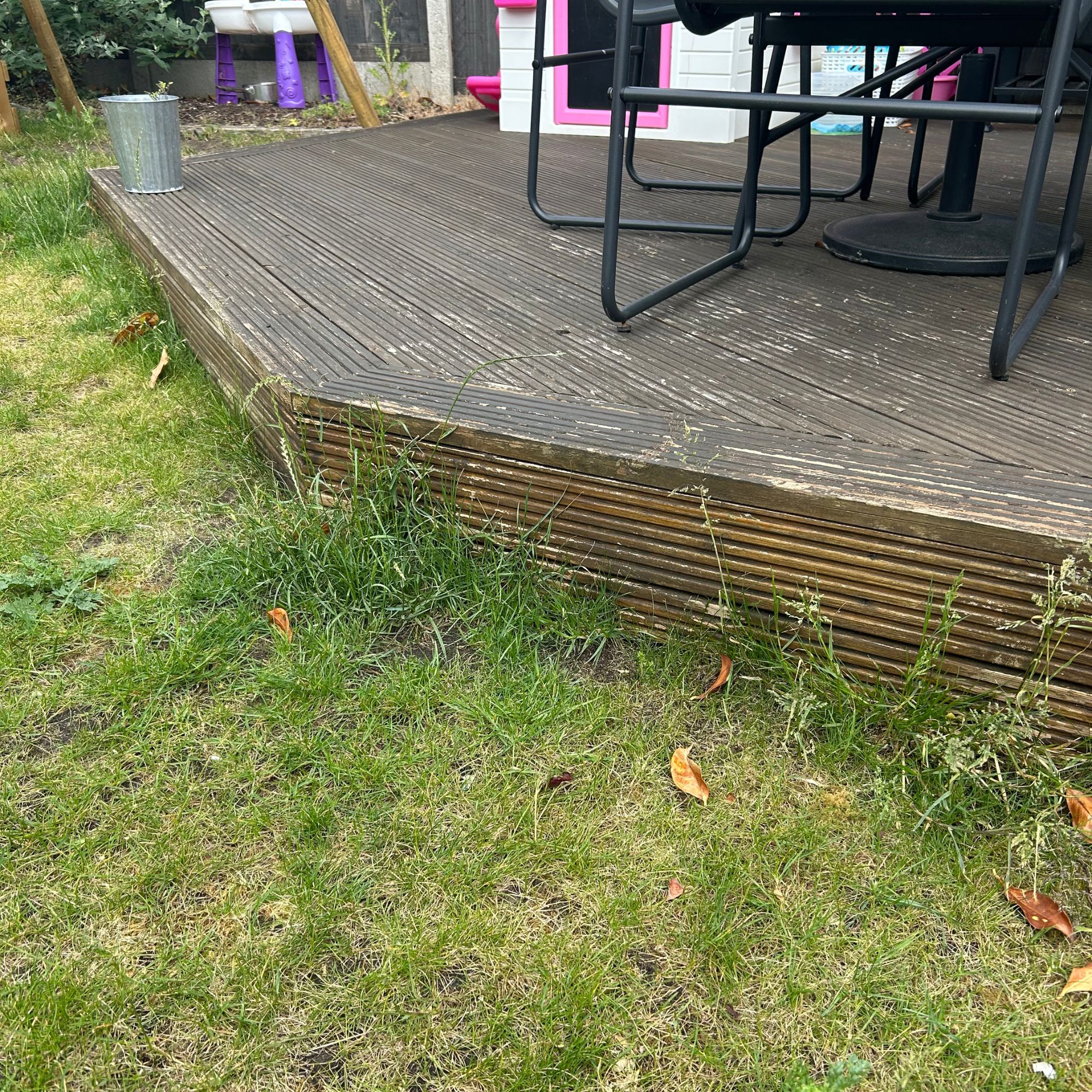 Corner of decking with long grass before mowing