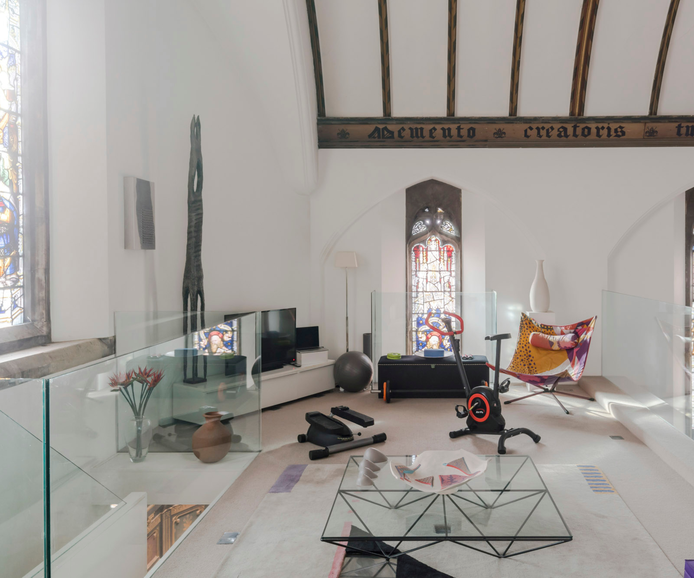 home gym on mezzanine level with glass wall and stained glass window