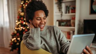 woman by Christmas tree on video call on tablet