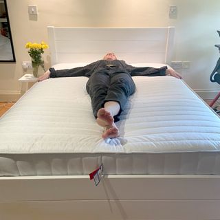 A woman laid spread eagle on the Dreams Workshop Follows Traditional Spring Mattress wearing a black denim jumpsuit