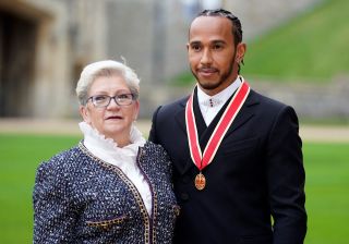 Why is Lewis Hamilton changing his name? TOPSHOT - Mercedes' British driver Lewis Hamilton stands with his with his mother Carmen Lockhart, as he poses with his medal after being appointed as a Knight Bachelor (Knighthood) for services to motorsports, by the Britain's Prince Charles, Prince of Wales, during a investiture ceremony at Windsor Castle in Windsor, west of London on December 15, 2021. - Lewis Hamilton received his knighthood on Wednesday as the British driver comes to terms with controversially losing the Formula One world title. (Photo by Andrew Matthews / POOL / AFP) (Photo by ANDREW MATTHEWS/POOL/AFP via Getty Images)