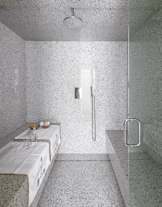 walk in shower with all round terrazzo tiles, shower benches, glass shower door