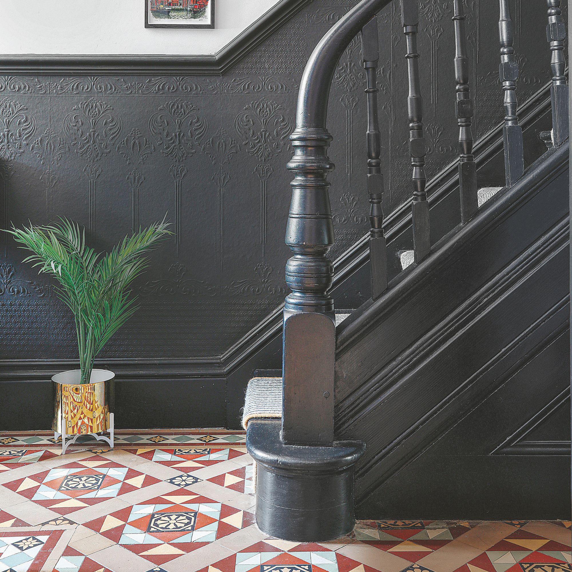 Black painted hallways with colourful tiled floor and a black bannister