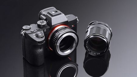 K&F Concept M42 for Sony E-mount vintage lens adapter mounted to a Sony camera on a black background with a reflective surface and a vintage lens placed next to it