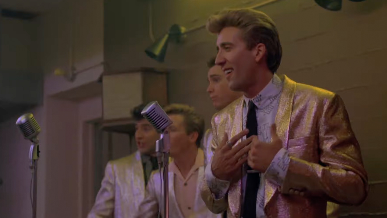 Nic Cage, in a sparkly pink suit and pompadour, performs in Peggy Sue Got Married.