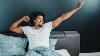 man smiling and stretching in bed