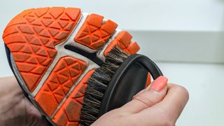 Woman cleaning a running shoe with a stiff brush