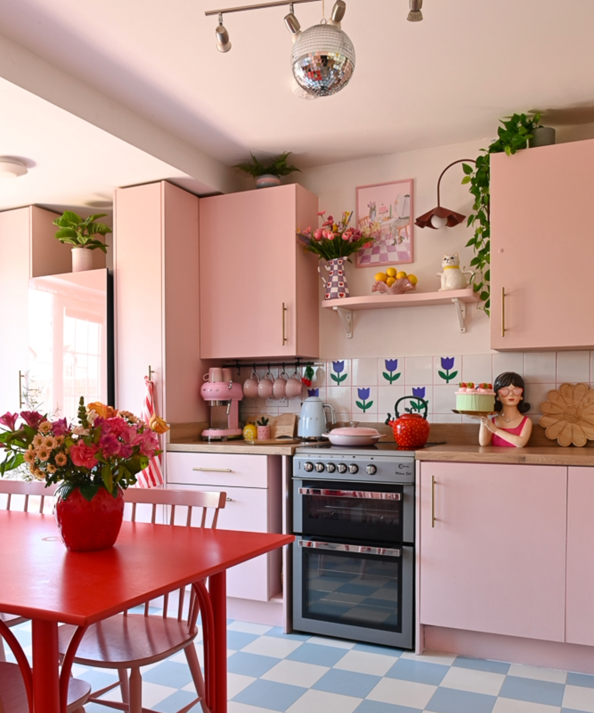 Kitchen with red table, pink cabinet doors, and blue and white flooring