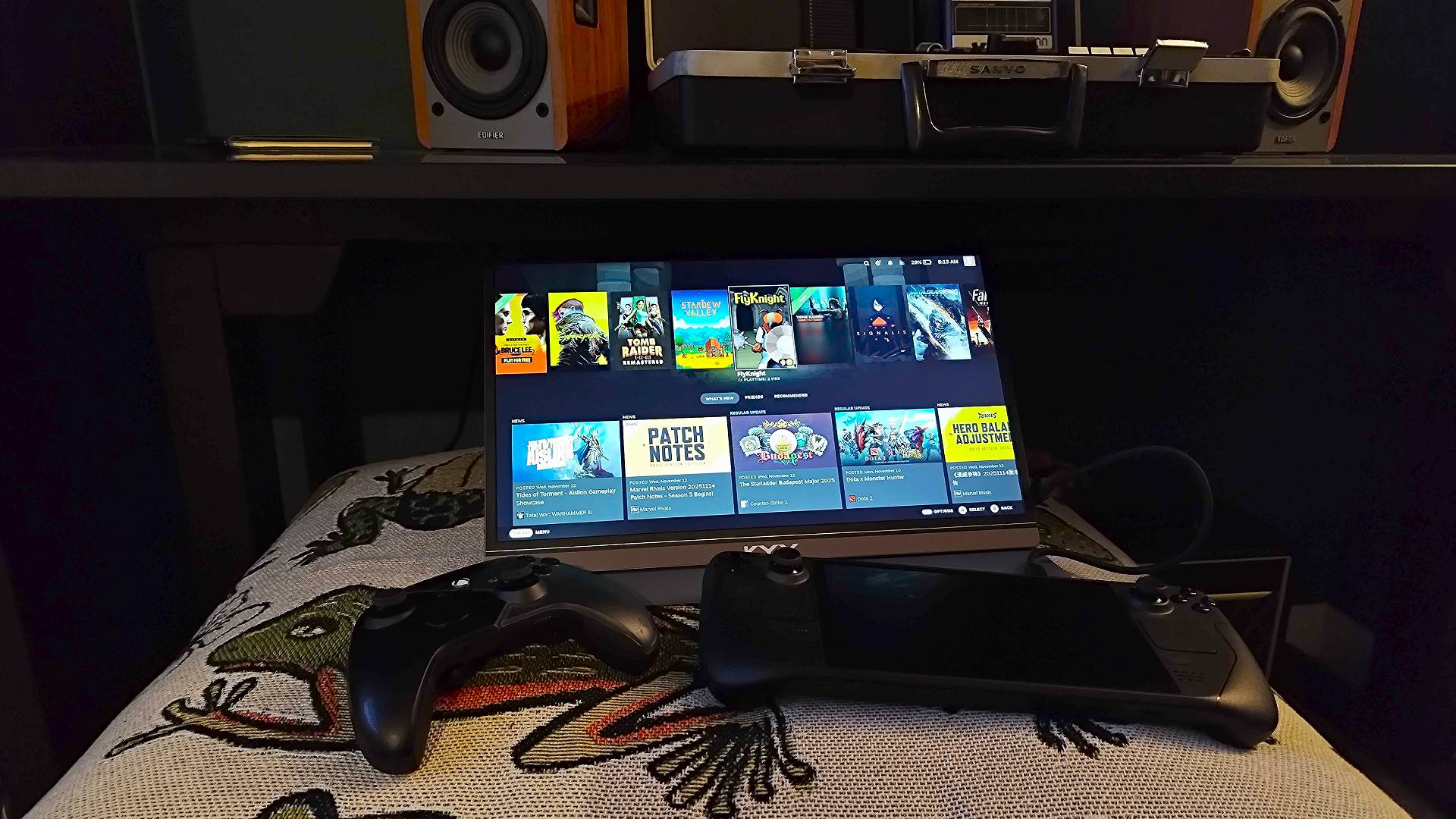 KYY Portable Monitor next to Steam Deck OLED and controller on top of blanket.