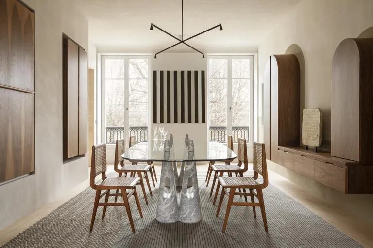 Apartment XVIII by Studio Razavi Architecture - a large glass table with six wood chairs; two floor to ceiling balcony doorways. An X shaped hanging light fixture.