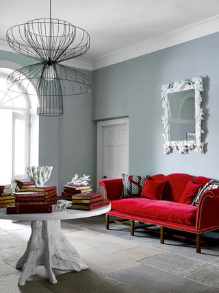Grey hallway with red sofa and statement ceiling light