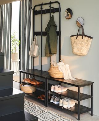 A hallway with a black coat and shoe storage unit