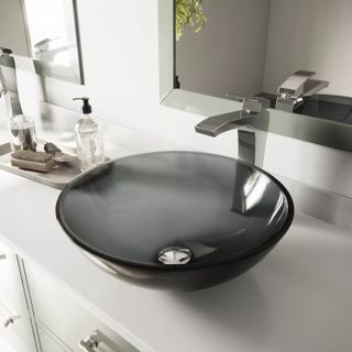 A grey glass vessel sink with chrome mixer tap