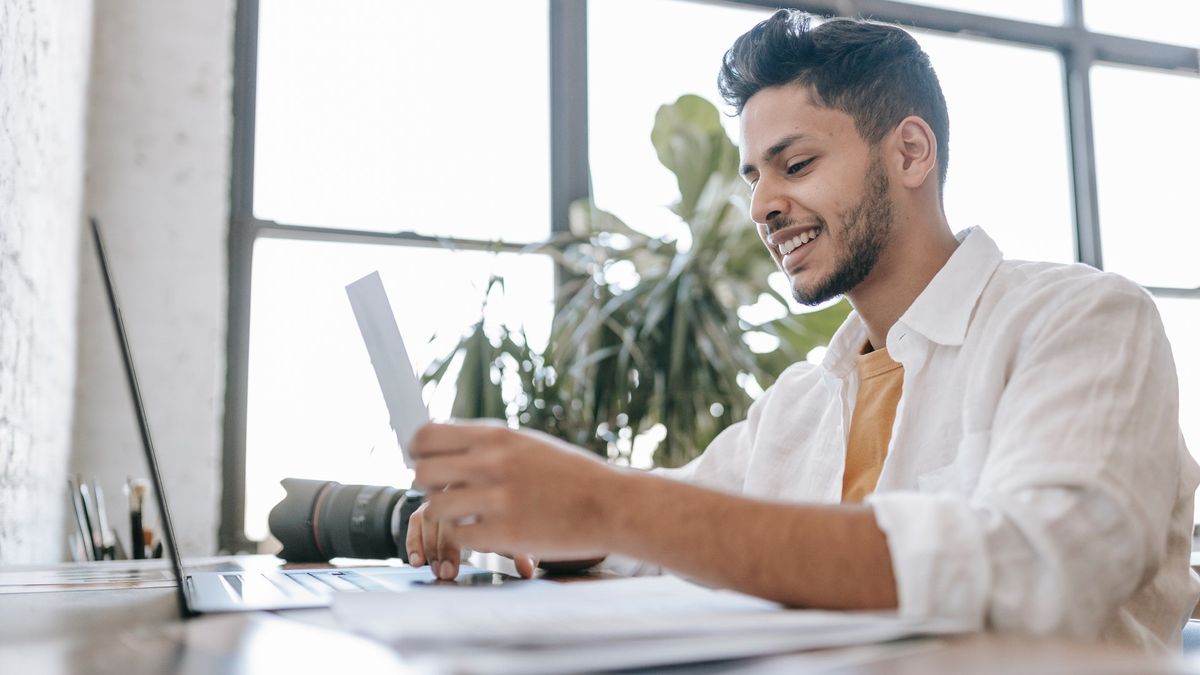 best antivirus software: Smiling man using laptop in front of office window