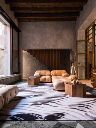 A black and white large-scale rug features abstract design, reviving the mid-century modern decor and brutalist frame of the home it is placed within.