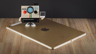 A Polaroid Funki Pop! standing on top of an iPad Air 2 on a wooden surface