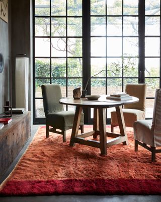 Thick orange rug in dining room with huge window