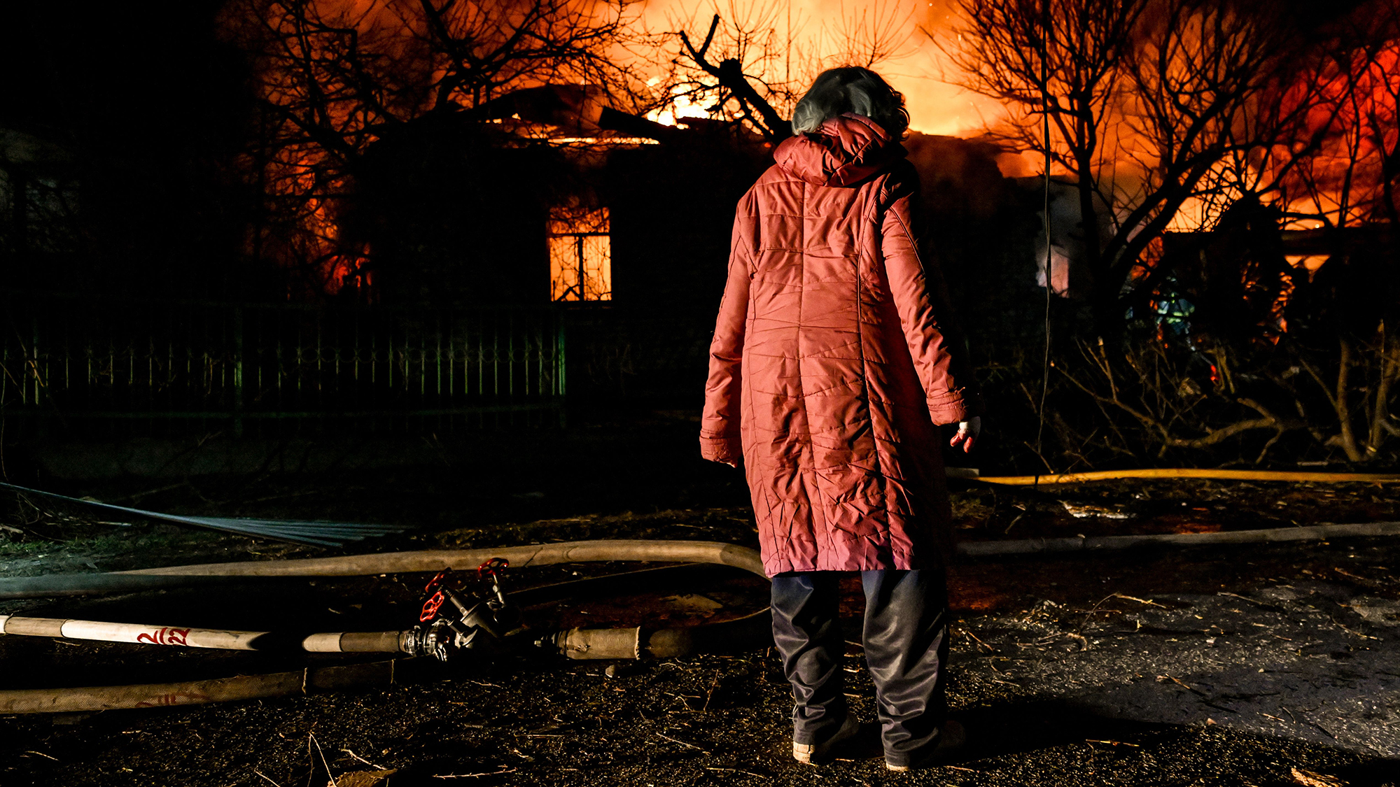 A woman watches as buildings burn following a Russian drone attack in Zaporizhzhia, Ukraine