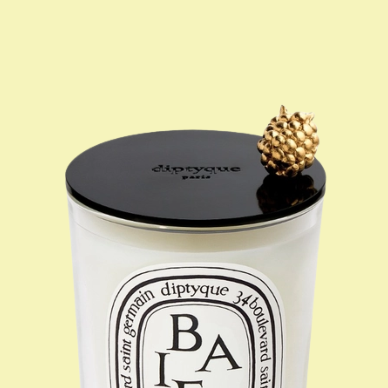 A candle with a black lid and a gold berry handle