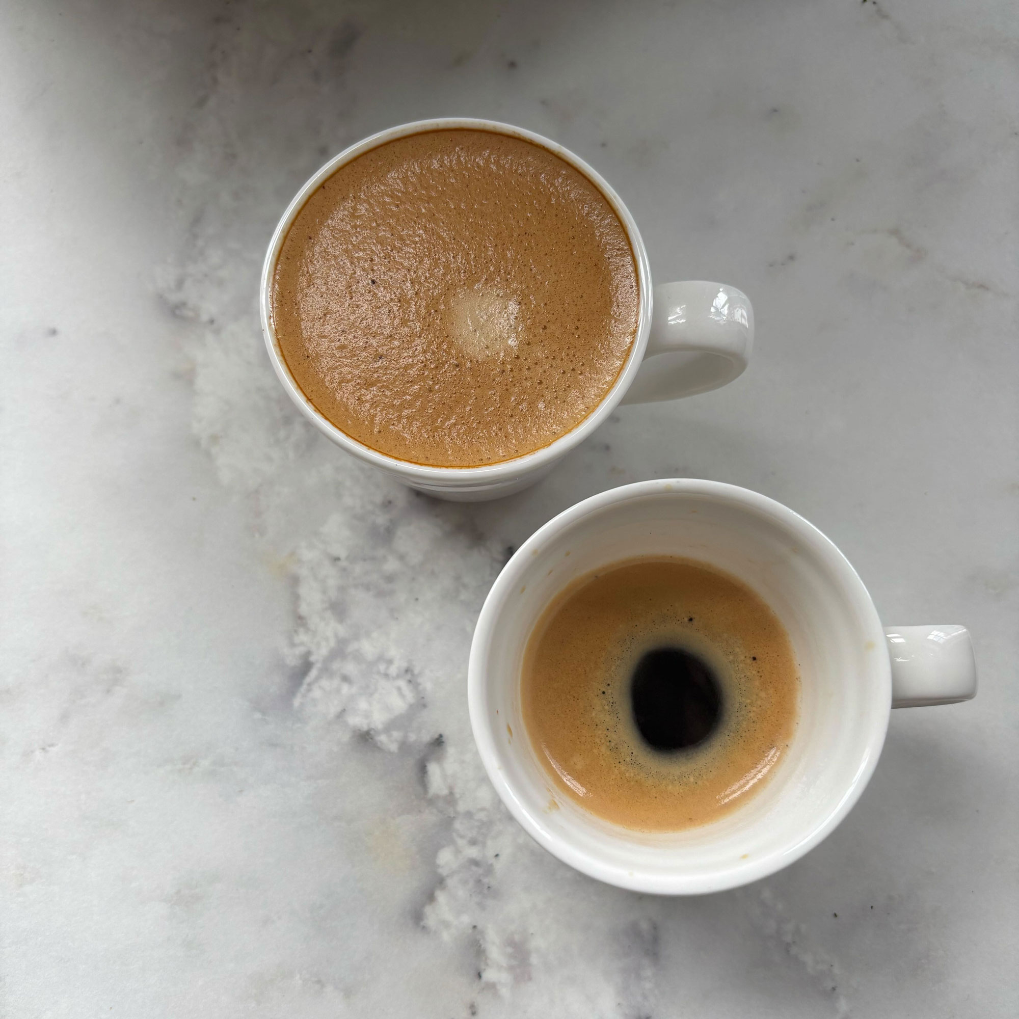 Two espresso cups one filled with lungo and one with espresso