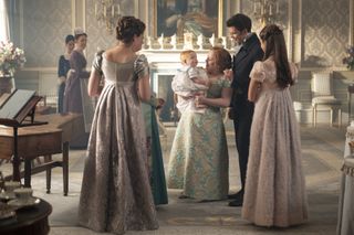 Penelope Bridgerton (Nicola Coughlan) holds her newborn son while surrounded by the Bridgerton family (from left: Ruth Gemmell as Violet Bridgerton, Luke Newton as Colin Bridgerton, Hannah Dodd as Francesca Bridgerton).