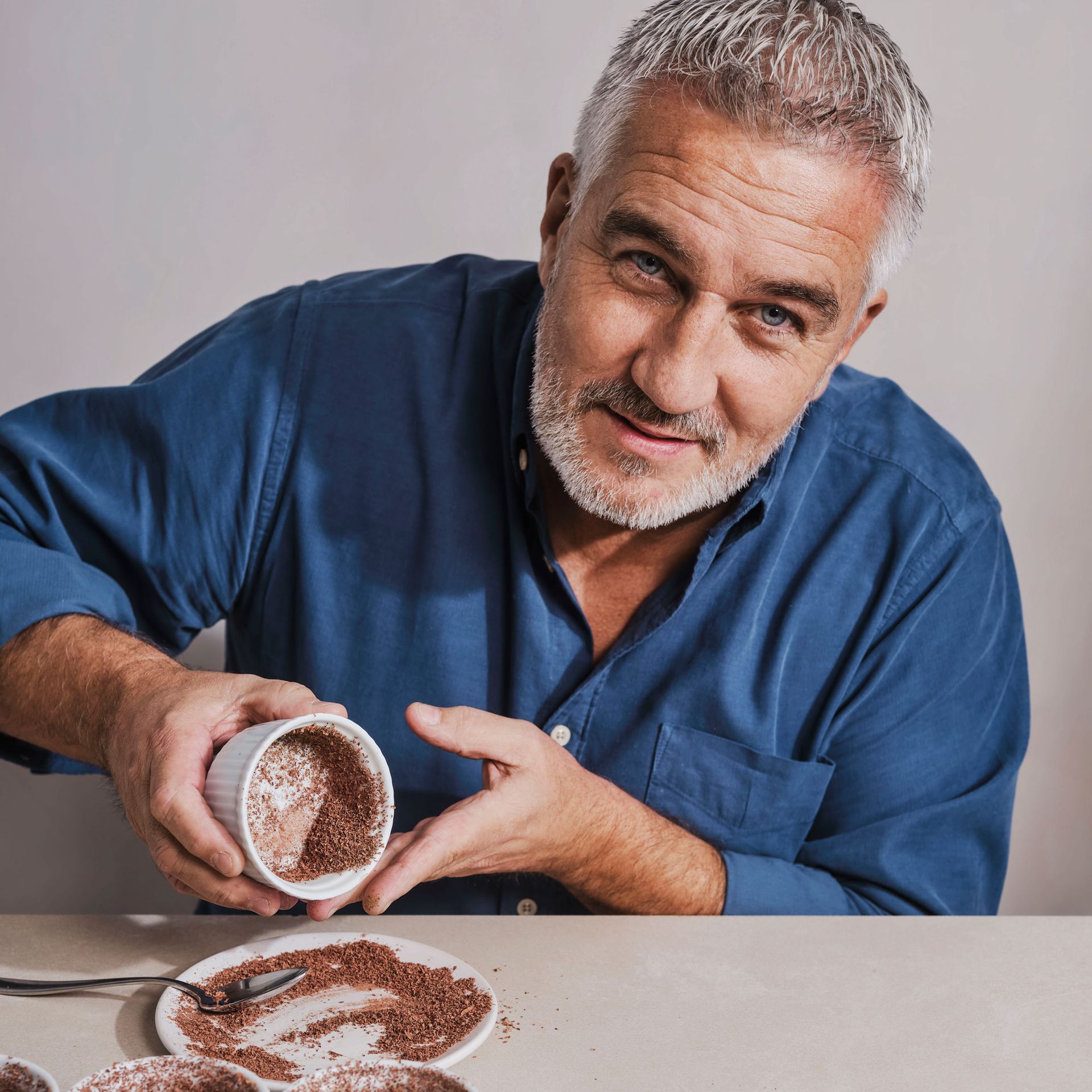 Paul Hollywood sprinkling chocolate into ramekin dishes