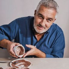 Paul Hollywood sprinkling chocolate into ramekin dishes