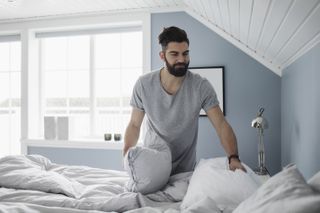 Man creating better sleep environment to stop himself having nightmares