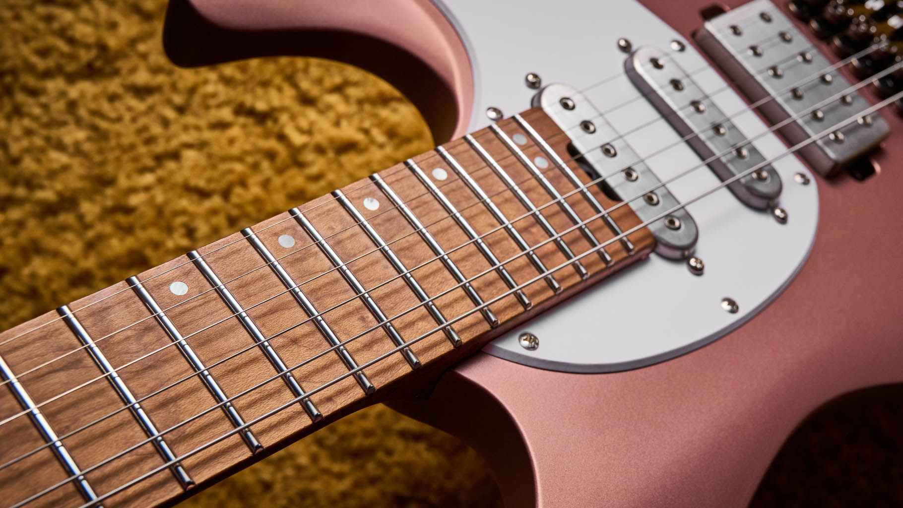 Ibanez Q54W: the headless electric guitar is finished in Copper Metallic Matte and photographed against a thick light-tan colored carpet.