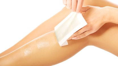 Close-Up Of Woman Waxing On Leg Over White Background - stock photo